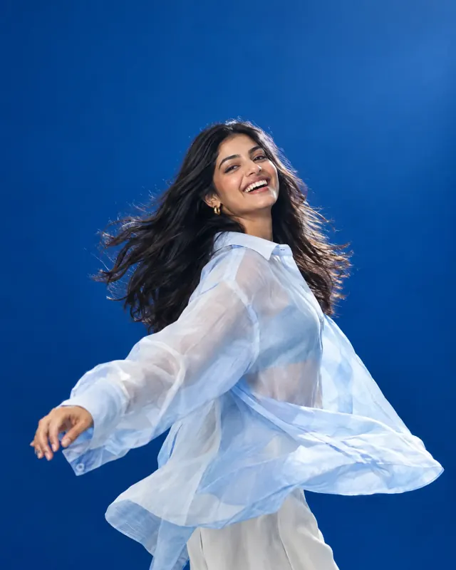 Young woman laughing and twirling in a flowing blue shirt